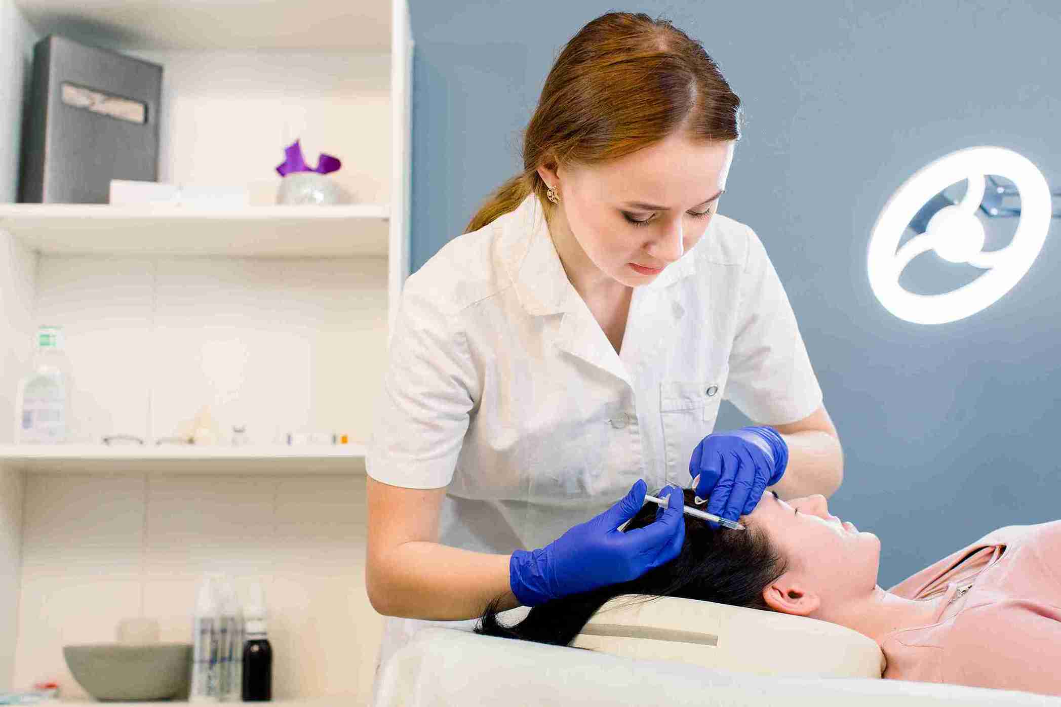 Especialista aplicando mesoterapia capilar con microinyecciones en el cuero cabelludo de una paciente para estimular el crecimiento y fortalecer el cabello.