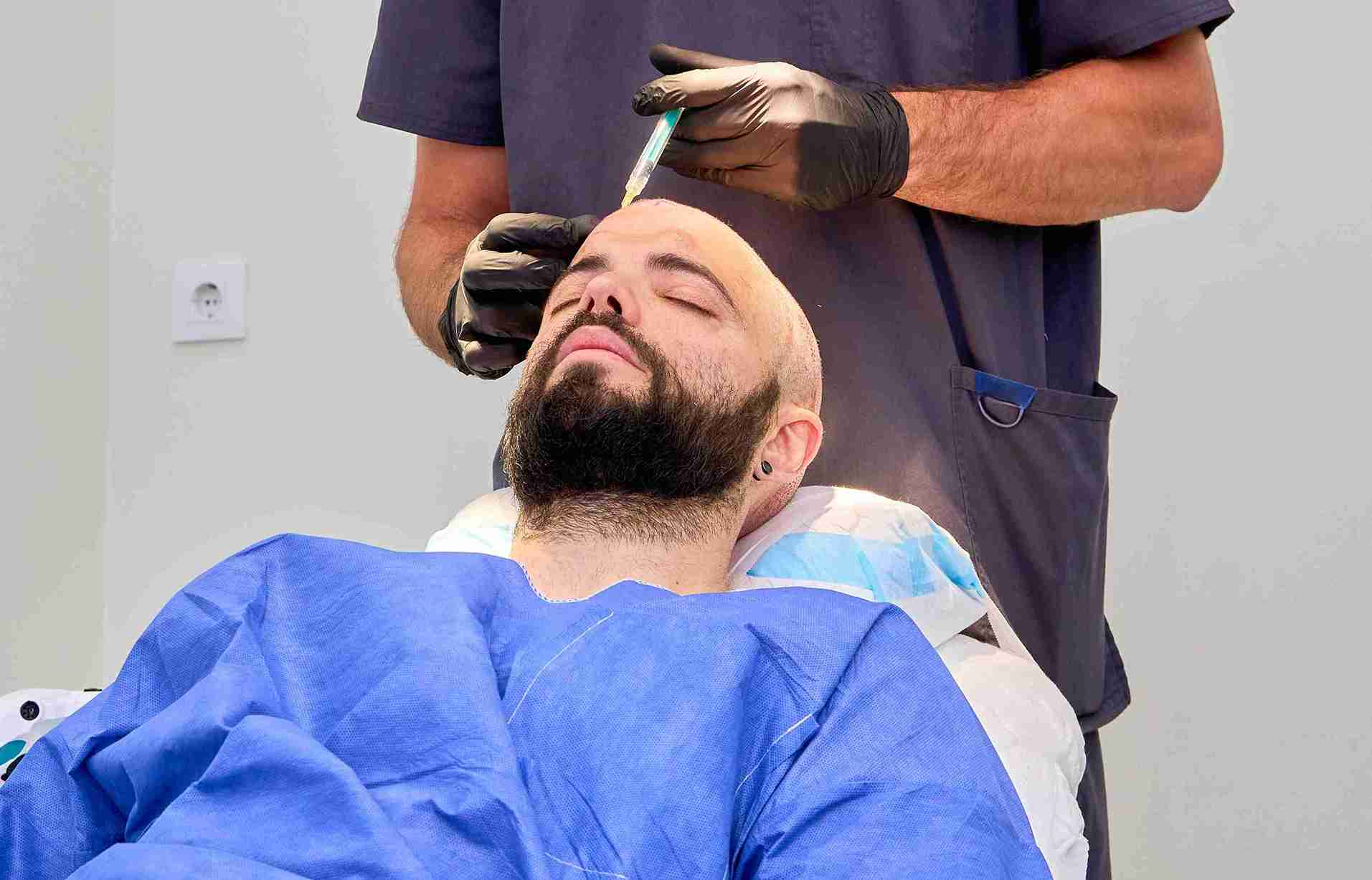 A patient undergoing a hair transplant procedure, with a doctor injecting the scalp under local anesthesia — an example to explain how does hair transplant work.